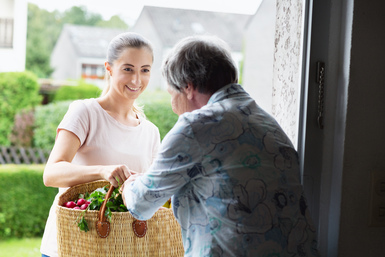 Frau bringt Einkäufe zu einer Dame nach Hause